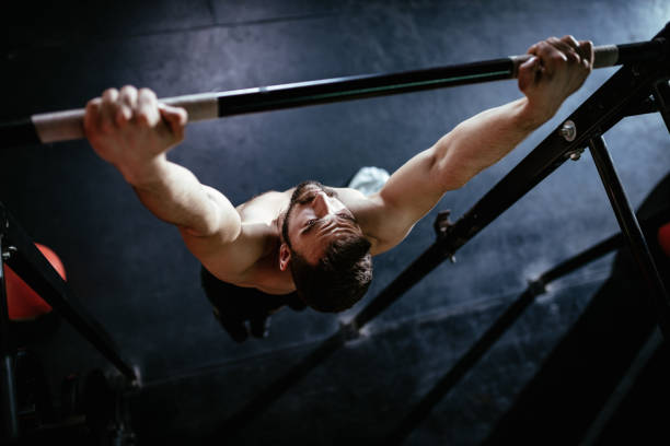 Athlete performing pull-ups in a dark gym